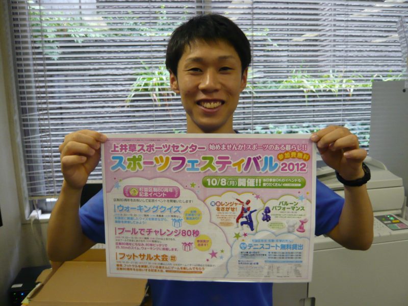 スタッフ矢谷くんが今年のチラシを持っています!